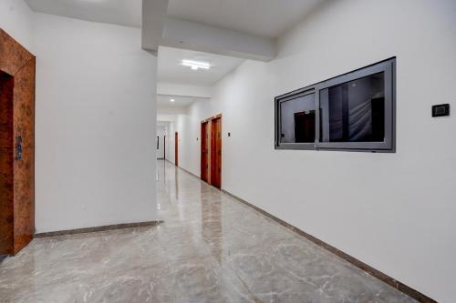 pasillo con paredes blancas y TV en la pared en Collection O Kanifnath Trek Pune, en Jadhavwadi