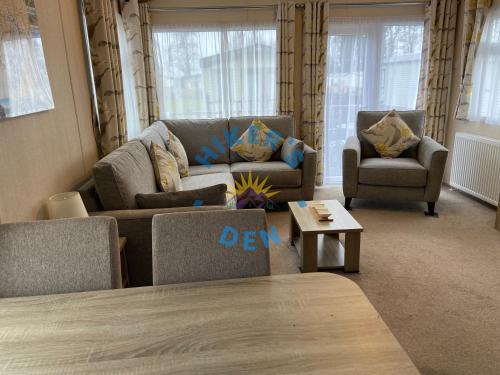 a living room with two couches and a table at Hikers Den, Brigham, Cockermouth, Cumbria in Cockermouth