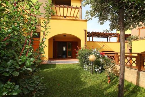 une grande maison jaune avec une cour dans l'établissement Trilocale Cielo, à Alberese