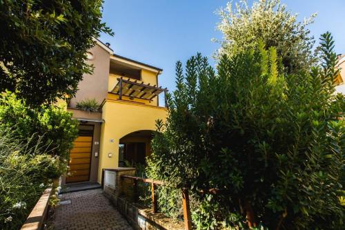 une maison jaune avec une passerelle devant elle dans l'établissement Trilocale Cielo, à Alberese