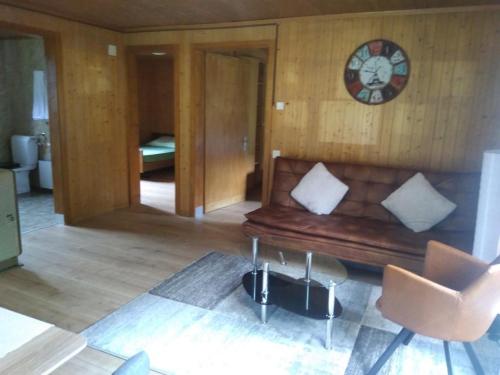 ein Wohnzimmer mit einer Couch und einer Uhr an der Wand in der Unterkunft Ferien Cottage Flüehblüemli in Stechelberg