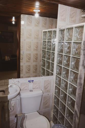 a bathroom with a toilet and a sink and a mirror at Coruja Suites - Ilha Grande in Abraão