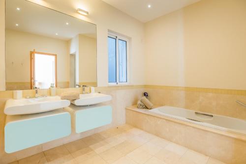 a bathroom with two sinks and a tub and a mirror at Villa La Terrasse by HR Madeira in São Gonçalo