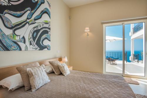 a bedroom with a bed with a view of the ocean at Villa La Terrasse by HR Madeira in São Gonçalo