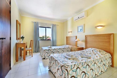 une chambre d'hôtel avec deux lits et une table dans l'établissement Villa Eira by Villa Plus, à Praia do Carvoeiro