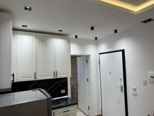 a kitchen with white cabinets and a black counter top at Shengjin apartaments in Lezhë