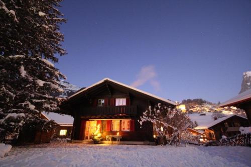 a log cabin in the snow at night at Chalet Gletscherfloh in Grindelwald