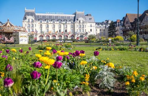 un champ de fleurs devant un grand bâtiment dans l'établissement Appartement deux pièces élégant avec Vue sur Parc - Plage & Centre-Ville à Pied, à Cabourg