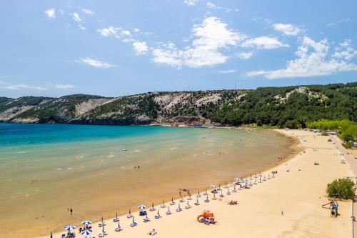 a beach with a group of umbrellas and people at Apartments BePa in Lopar