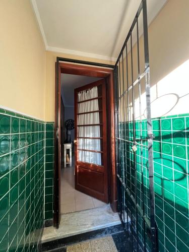 a bathroom with green tiled walls and a wooden door at Casa en zona centro in Necochea