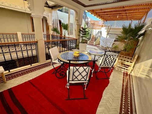 a balcony with a table and chairs on a red rug at Riad Rose Mati in Marrakech