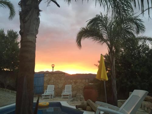 a view of a sunset from a pool with palm trees at Villa Antonella in Villasimius