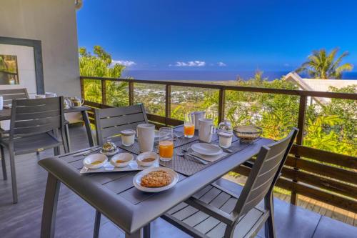 einen Tisch mit Frühstückszutaten auf einem Balkon mit Meerblick in der Unterkunft Villa Romeo in L’Étang-Salé