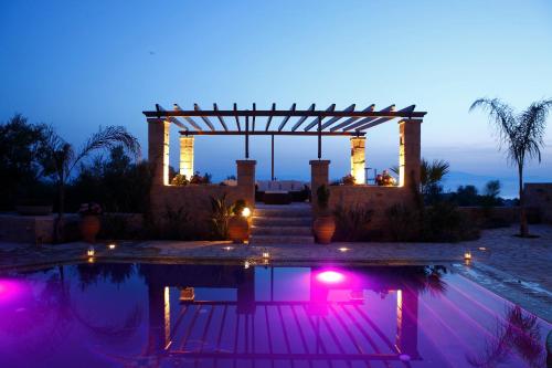 a swimming pool with a gazebo at night at Olympia Villas in Stoupa