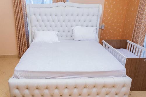 班布里Kerith Springs Family Holiday home Bamburi Msa的一张白色的床,位于一个配有婴儿床的房间