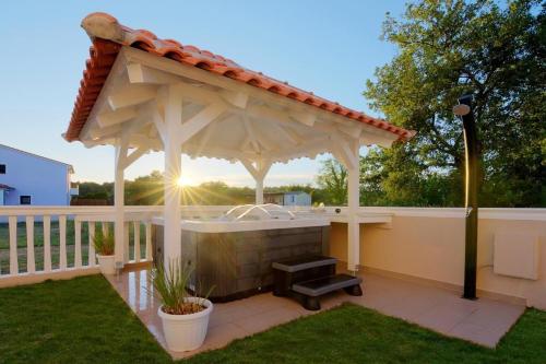 einem hölzernen Pavillon mit einer Bank im Hof in der Unterkunft Moderne Ferienwohnung mit jacuzzi in Ližnjan