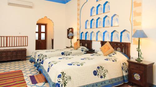 a bedroom with two beds with blue and white sheets at Dera Mandawa in Jaipur