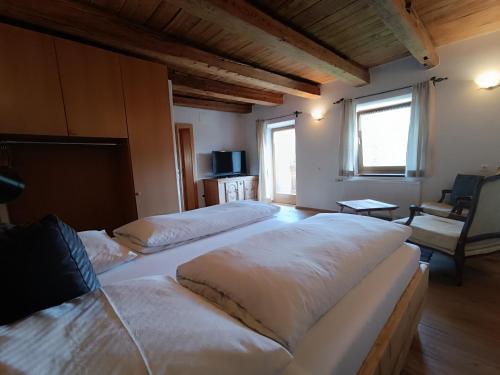 a room with three beds and a chair and a television at Pension Ferienwohnungen Marchnerhof in Terento