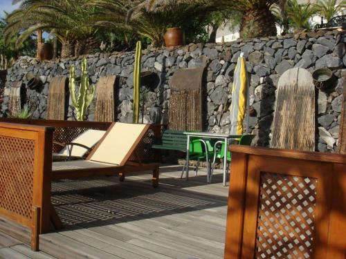 eine Terrasse mit Stühlen, einem Tisch und einer Steinmauer in der Unterkunft Kleines Ferienhaus mit eigener, teils überdachter Terrasse in Alcalá