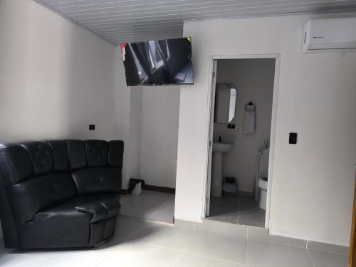 a living room with a black leather couch and a television at Hotel coral Issa in Bahía Solano