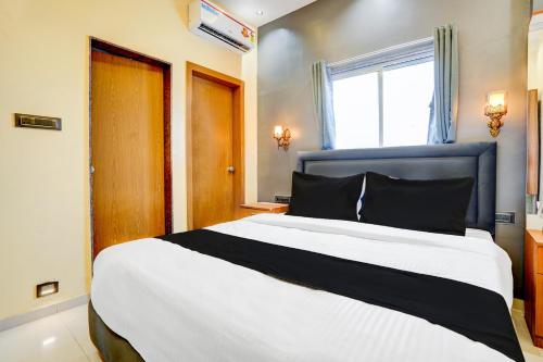 a bedroom with a large white bed with a blue headboard at Hotel O Fortune Palace in Hinjewadi