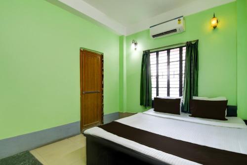 a bedroom with a bed with green walls and a window at Hotel O Sampad in Baharampur
