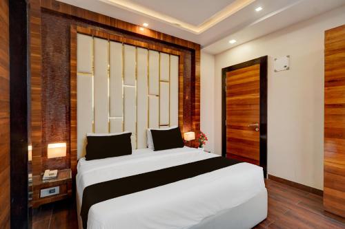 a bedroom with a white bed and a wooden wall at Townhouse Oak CSJMU Kanpur Formerly Shree Dev Villa in Kaliānpur