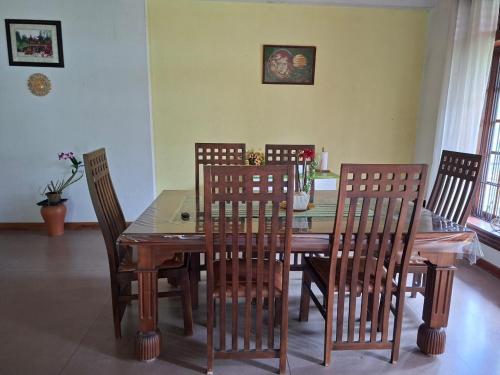 Un comedor con mesa y sillas de madera. en ADLi, en Pambahinna