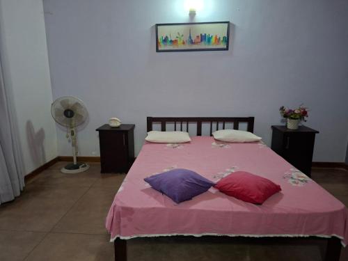 Un dormitorio con una cama rosa con tres almohadas. en ADLi, en Pambahinna