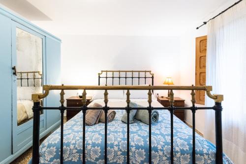 ein Schlafzimmer mit einem Metallbett mit einer blauen Tagesdecke in der Unterkunft L57 - Habitaciones en Órgiva in Órgiva