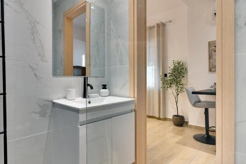 une salle de bain blanche avec un lavabo et un miroir dans l'établissement CityLife studio 2'from metaxourgio station 2A, à Mesochórion