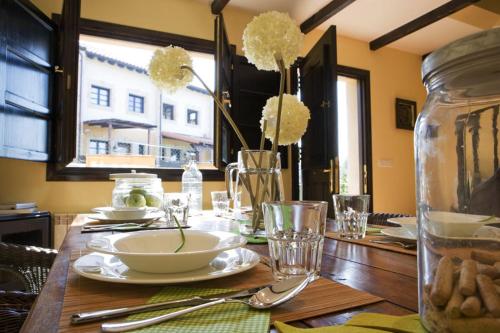 a wooden table with plates and a vase with flowers at Apartamentos Santillana del Mar in Santillana del Mar