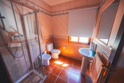 een badkamer met een douche, een toilet en een wastafel bij La Llave Rural in Benaocaz