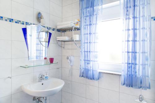 ein weißes Bad mit einem Waschbecken und einem Fenster in der Unterkunft Pension Sieg in Rust