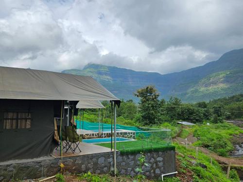 a building with a tent next to a river at Streaming Offline Karjat - Premium Tent Stay with Private Plunge Pool in Jambrung 
