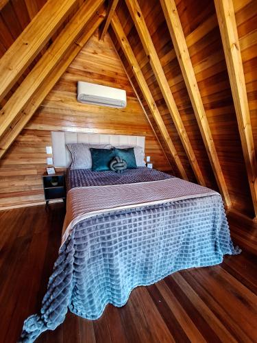 a bedroom with a bed in a wooden attic at Cabanas Céu e Mel - Cabana 01 in Bom Retiro