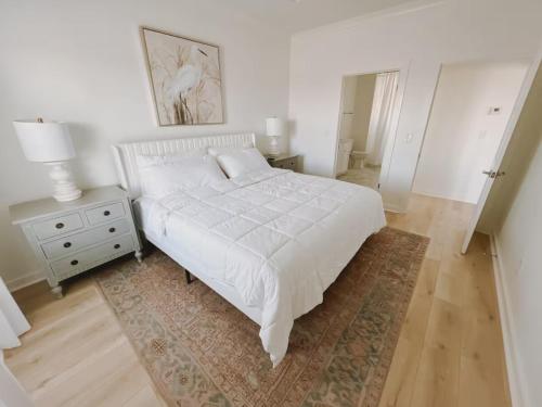 Starfish Room #1 في Pass Christian: غرفة نوم بيضاء مع سرير وموقف ليلي