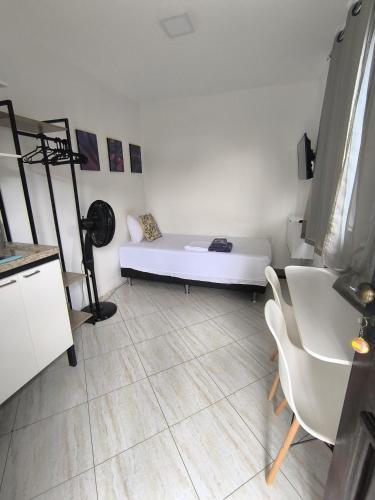 a white room with a bed and a chair at Vaccani Apart in Macaé