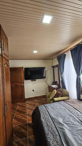a bedroom with a bed and a flat screen tv at Casa campestre cerca de termales con WiFi y parqueadero in Santa Rosa de Cabal