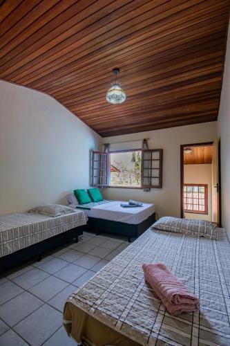 a bedroom with two beds and a wooden ceiling at Casa em condomínio com piscina in Paraty