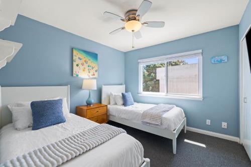 a blue bedroom with two beds and a ceiling fan at Ocean Breeze Getaway - Solana Beach Condo in Solana Beach