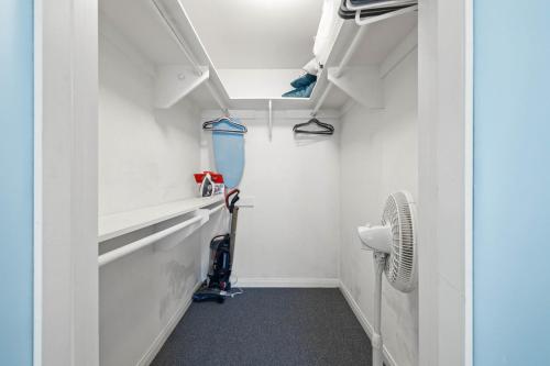 a bathroom with white walls and a room with a vacuum at Ocean Breeze Getaway - Solana Beach Condo in Solana Beach