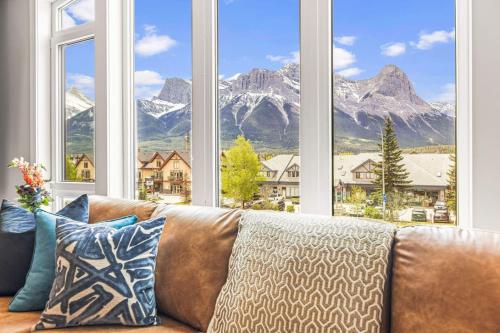 a couch in front of a large window with mountains at Luxury 4BR with Hot Tub Mtn Views 10Min Walk to DT in Canmore