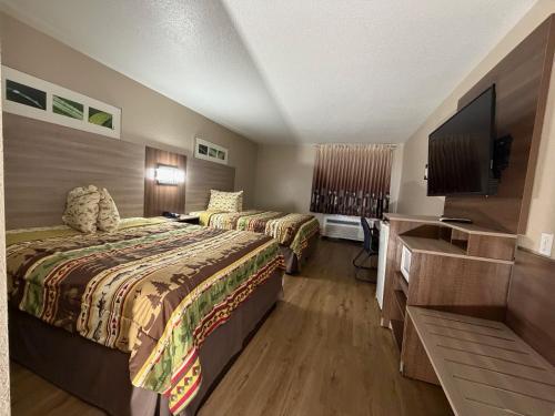 a hotel room with two beds and a flat screen tv at Booneslick Lodge - Neosho in Neosho