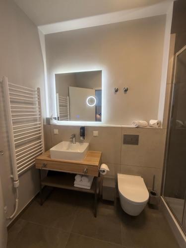 ein Badezimmer mit Waschbecken, Toilette und Spiegel in der Unterkunft H24 Parkhotel Thale in Thale