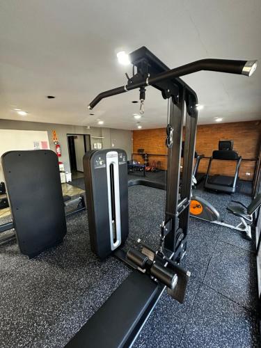 une salle de sport avec un tapis roulant et une valise posée au sol dans l'établissement Flat Completo - Praia de Jatiuca, à Maceió