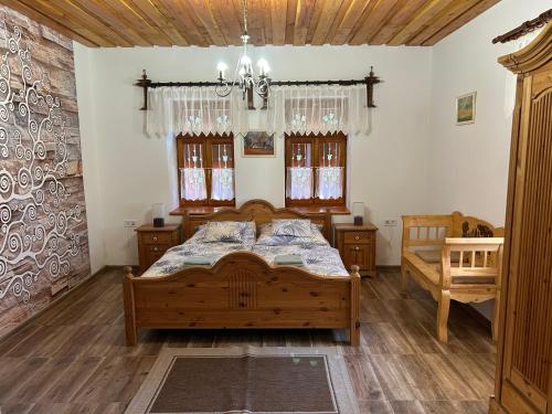 a bedroom with a wooden bed and two windows at Panoráma Terasz Vendégház in Noszvaj