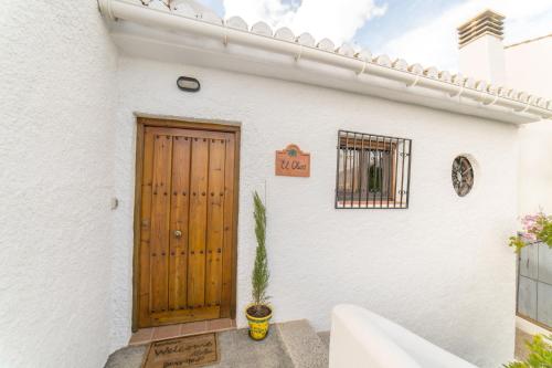a white house with a wooden door and a plant at Casa El Olivo, Landhaus Mit Bergblick in Dúrcal