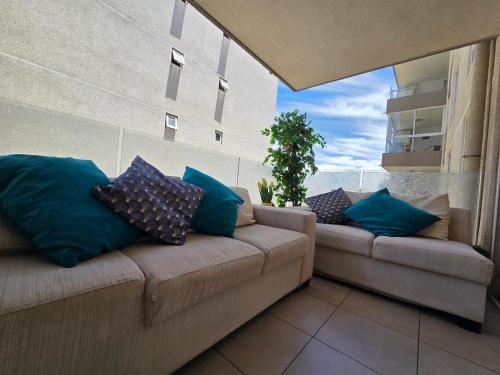 d'un canapé avec des oreillers bleus assis sur un balcon. dans l'établissement Arriendo departamento en La Serena Central, à La Serena
