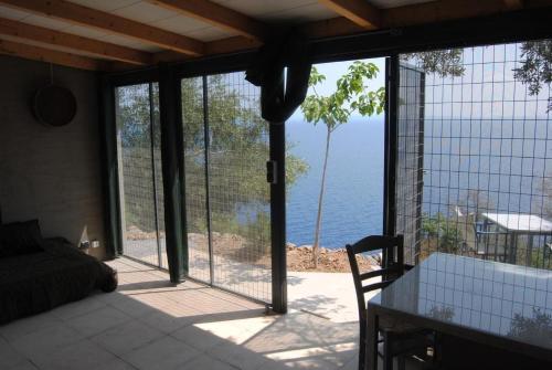 ein Zimmer mit Blick auf das Meer durch Glasschiebetüren in der Unterkunft Leonidionhouses - Der Kleine Bungalow in Leonidi